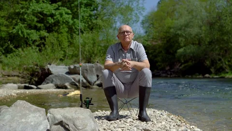 Happy Old Man With Fishing Rod Sitting Next To River Smiling At Camera Stock Footage 112637726