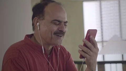 A happy old man using smartphone to chat with a wife over a video call Stock Footage 125354970