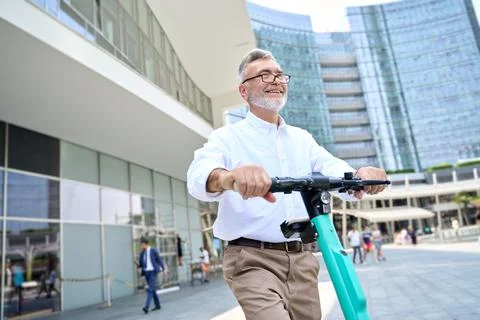 Happy older man using mobile app for bike rental renting bike in city park. Stock Photos