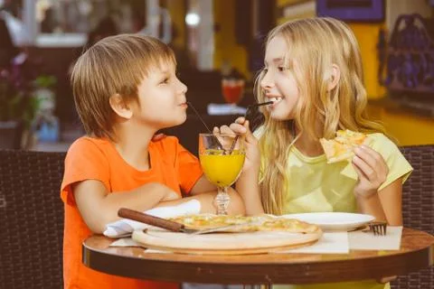 Happy or satisfied boy width girl eating pizza and drinking juice Stock Photos