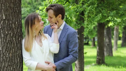 Happy pair caresses near tree in city garden at spring day, slow motion Stock Footage 276361905