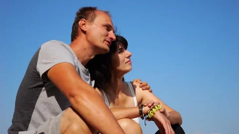 Happy pair hugs during sitting on wooden log on beach. Romantic couple admiring  Vídeo Stock 344041105