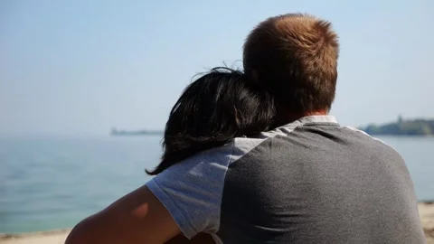 Happy pair hugs during sitting on wooden log on beach. Romantic couple admiring  Vídeo Stock 344041163