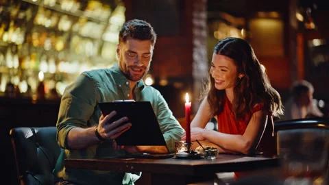 Happy pair looking menu at romantic date in bar closeup. Smiling couple talking Vídeo Stock 334009112
