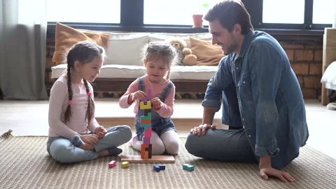 Happy parent dad helping daughters playing toys together on floor, having fun Vídeo Stock 147388798