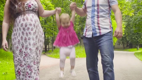 Happy parents with baby girl walking in a park Stock Footage