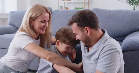 Happy parents having fun tickling with little child boy sitting on floor at home Stock Footage 308664260