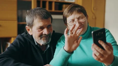 Happy parents look at the phone while sitting in the living room and smile. Stock Footage 243510992