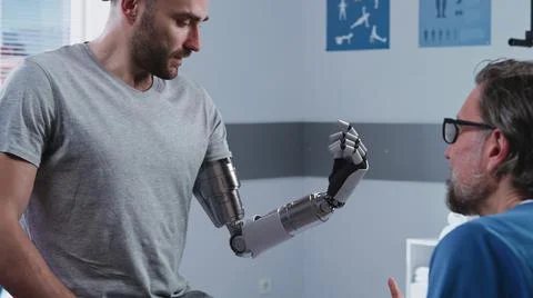Happy patient learning to use bionic arm near doctor Stock Photos