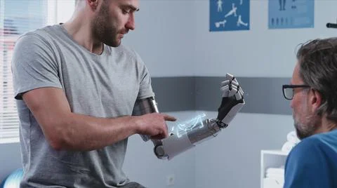Happy patient learning to use bionic arm near doctor Stock Photos