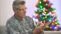 The happy pensioner sit with a tablet near the christmas tree. evening time 4k or 4k+ Resolution