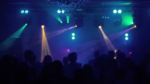 Happy people dance under the rays of light devices, raising their hands up Stock Footage 200880914