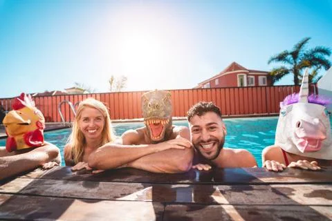 Happy people doing pool private party while wearing funny animals masks - You Stock Photos
