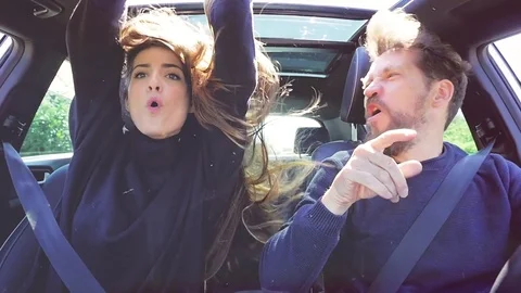 Happy people driving car dancing with wind blowing hair looking camera slow m Stock Footage 76779490