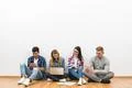 The happy people with gadgets sit on the floor on the white wall background Photo