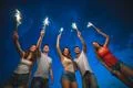 The happy people hold firework sticks. evening night time Photo