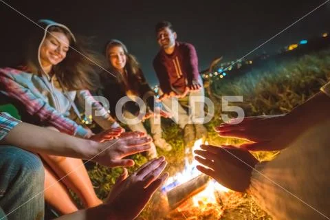 The happy people warming hands near the bonfire. night time Stock Photos
