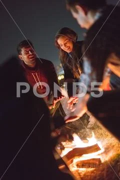 The happy people warming hands near the bonfire. night time Stock Photos