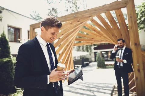 Happy person looking at the tablet while his friend talking on the phone Stock Photos