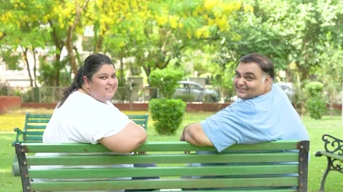 Happy Plus size indian couple sitting together at summer park. Overweight m.. Stock Footage 312908307