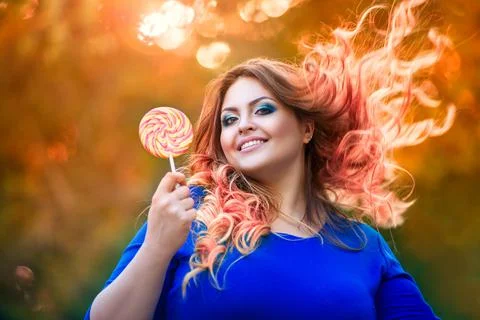 Happy plus size model with big lollipop outdoors, fat woman in autumn park am Photos