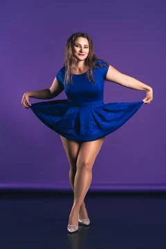 Happy plus size model in blue dress on purple background Photos