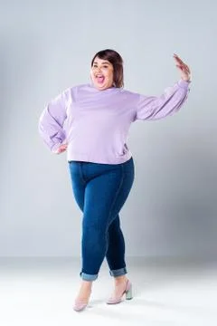 Happy plus size model in casual clothes, fat woman on gray background, body p Foto stock
