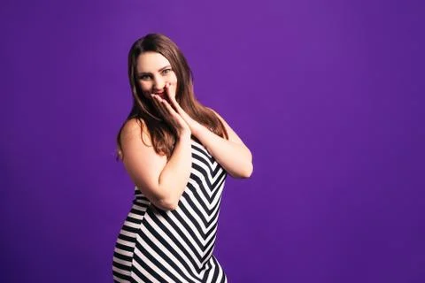 Happy plus size model in striped dress, fat woman on purple background Photos