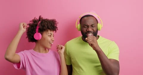 Happy positive dark skinned young woman and man dance and enjoy music sing Stock Footage 151196811