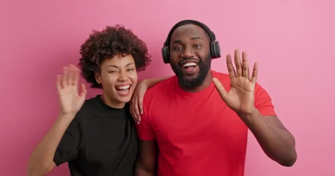 Happy positive friendly Afro American couple glad to meet friend wave palms look Stock Footage 152536161