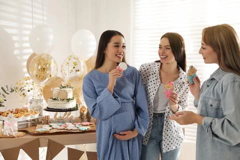 Happy pregnant woman and her friends with tasty cookies at baby shower party Stock Photos