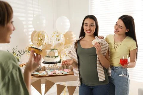 Happy pregnant woman and her friends with tasty treats at baby shower party Stock Photos