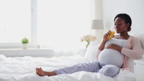 Happy pregnant woman drinking fresh orange juice Stock Footage