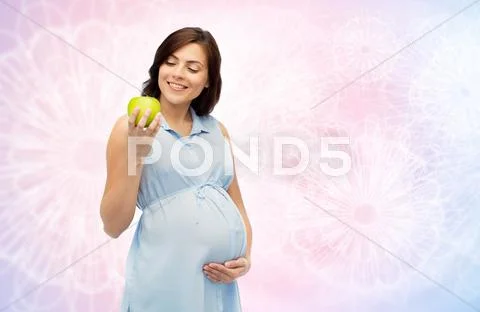 Happy pregnant woman looking at green apple Stock Photos