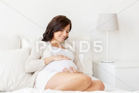 Happy pregnant woman lying on bed at home Stock Photos