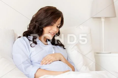 Happy pregnant woman lying in bed at home Stock Photos