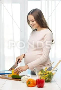 Happy pregnant woman preparing food at home Stock Photos