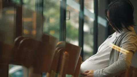Happy pregnant woman touch her belly in the cafe Stock Footage