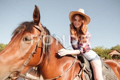 Happy pretty young woman cowgirl riding horse Stock Photos
