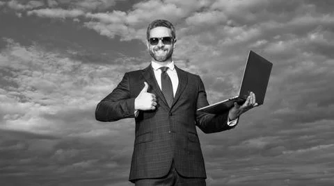 Happy programmer holding laptop. Computer programmer showing thumb gesture Stockfoto's