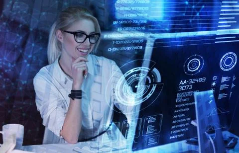 Happy programmer looking at the transparent screen of a computer and smiling Foto stock