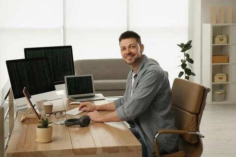 Happy programmer working at desk in office Stock Photos
