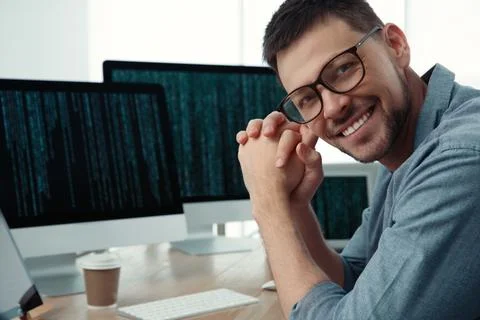 Happy programmer working at desk in office Stock Photos