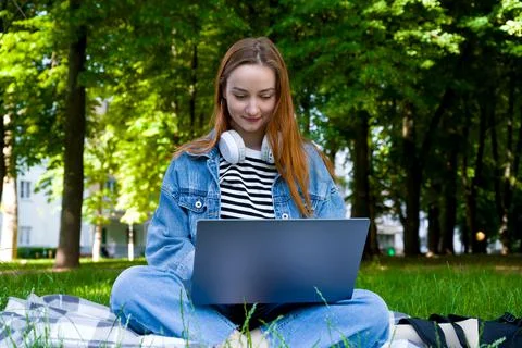 Happy red haired female using laptop for e-learning.Back to school concept.Di Stock Photos