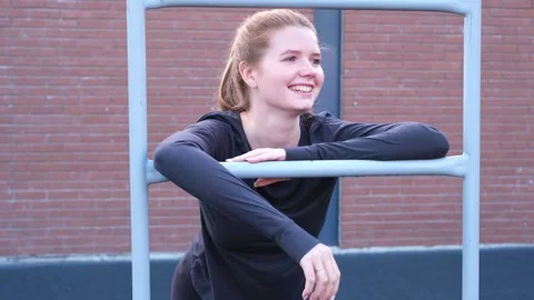 Happy red-haired girl doing fitness workout on sports ground in a summer Stock Footage 298296719