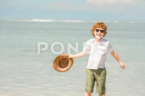 Happy red haired kid boy wearing hipster sunglasses waving hat enjoying Stock Photos