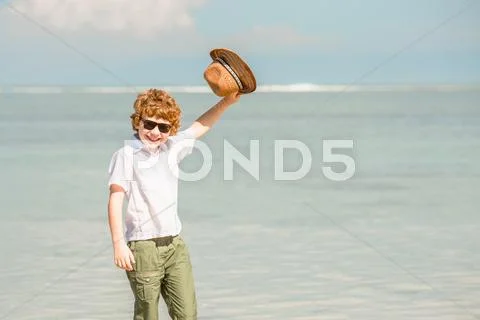 Happy red haired kid boy wearing hipster sunglasses waving hat enjoying Stock Photos
