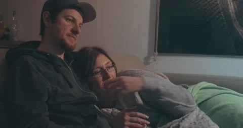 Happy Relaxed Couple Sit On Sofa and Watch Together Movie On Tv Stock Footage 144924375