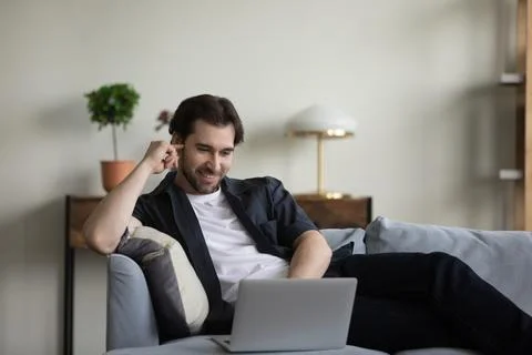 Happy relaxed millennial man using computer software apps. Stock Photos
