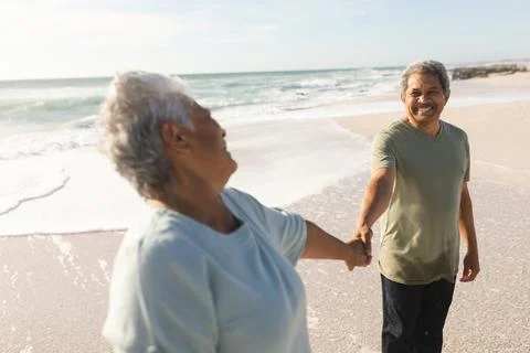 Happy retired senior multiracial couple holding hands while looking at each Stock Photos